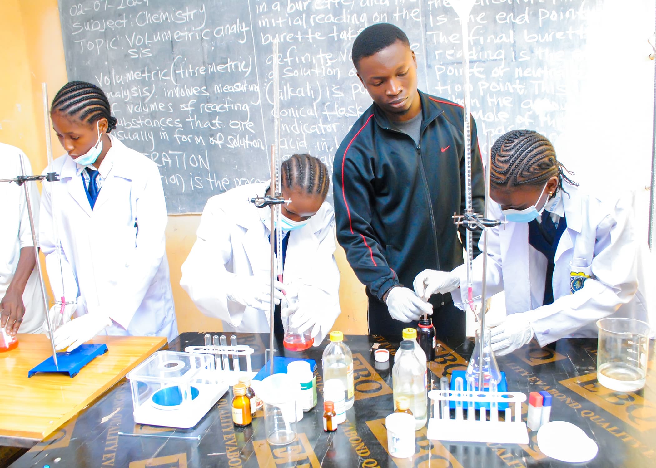 Students carrying out a chemistry experiment with their teacher